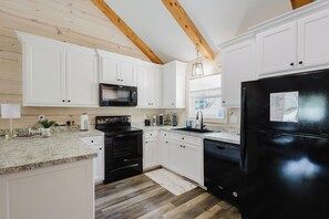 A modern kitchen with white cabinetry, a black refrigerator, and a built-in microwave. - Lakeside Retreat near Hot Springs - Swim & Unwind (Hot Springs)