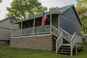 A two-story building with a porch, a flag, and a staircase leading to the upper level. - Lakeside Retreat near Hot Springs - Swim & Unwind (Hot Springs)