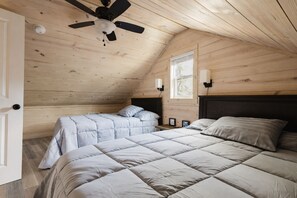 A bedroom with a sloped ceiling, a ceiling fan, two beds with matching bedding, a nightstand, and a window. - Lakeside Retreat near Hot Springs - Swim & Unwind (Hot Springs)
