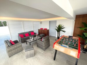 A modern living room with a foosball table, comfortable seating, and a large window.
