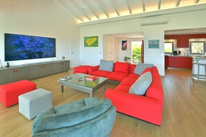 A modern living room with a sectional sofa, a glass coffee table, and a flat-screen TV.