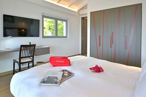 A bedroom with a bed, a desk, a chair, a TV, and a wardrobe.