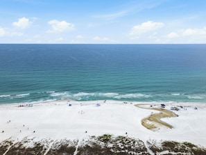 A beach with a clear view of the ocean, sandy shore, and a few umbrellas. - Luxury Coastal Retreat | Pool, Golf Cart & Gulf Views (Panama City Beach)