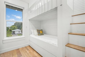 A room with a window, a built-in bench with a cushion, and a wooden floor. - Luxury Coastal Retreat | Pool, Golf Cart & Gulf Views (Panama City Beach)