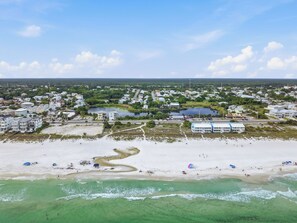 Luftaufnahme einer Küstenstadt mit Strand, Gebäuden und einem Yachthafen.