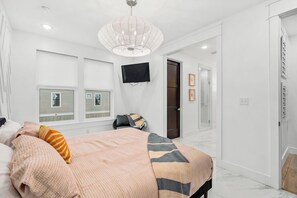 Ein Schlafzimmer mit einem Bett, einem Fernseher und einem Fenster mit Jalousien.