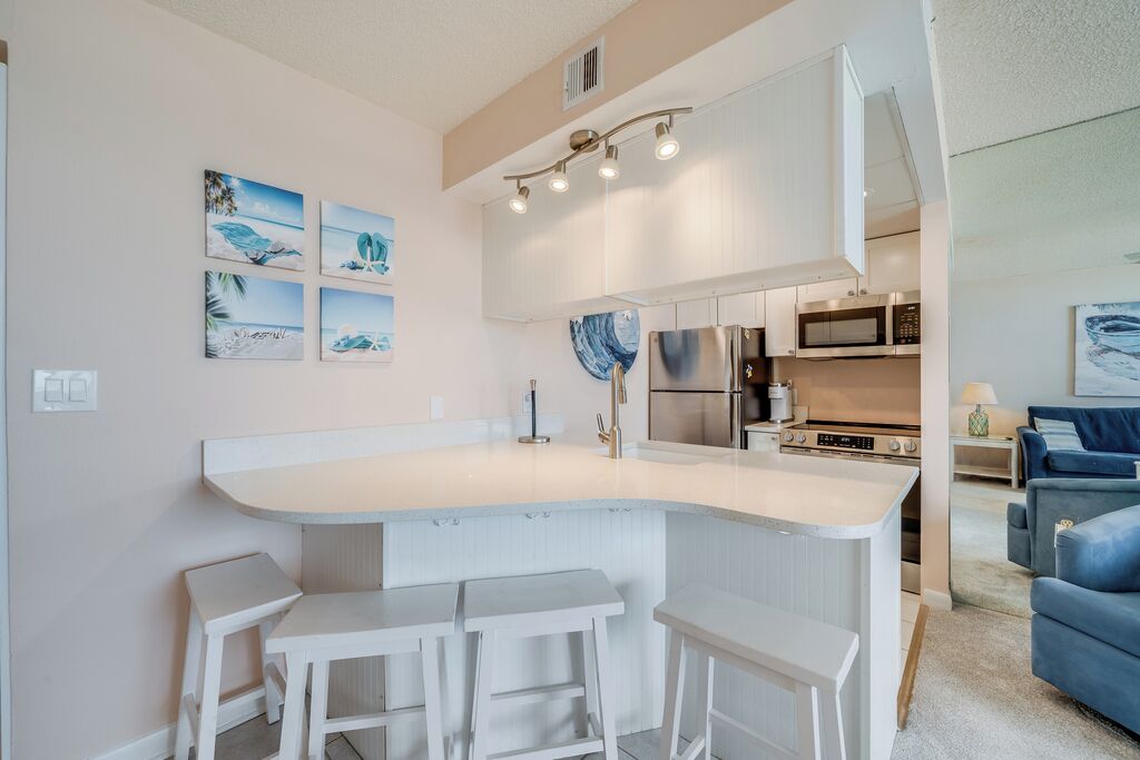 Uma cozinha moderna com uma ilha central, banquetas de bar e um espaço de refeições.