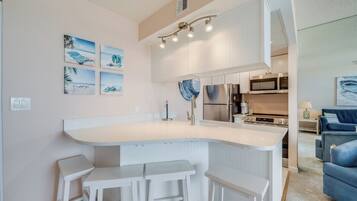Uma cozinha moderna com uma ilha central, banquetas de bar e um espaço de refeições.