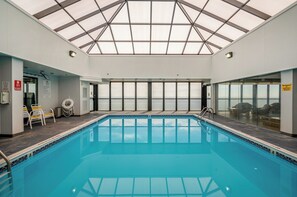 An indoor swimming pool with a glass ceiling, clear view of the sky, and a no-diapers sign. - Golden Sands 706 by Seaside Vacations & Sales (Ocean City)