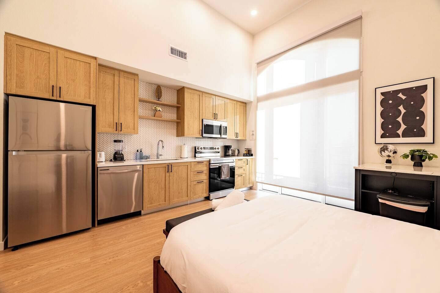 A modern kitchen with wooden cabinets, stainless steel appliances, and a large window providing natural light.