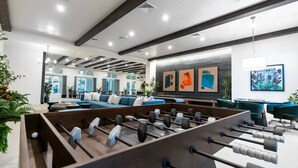 A modern indoor space with a foosball table, seating area, and artwork on the walls.