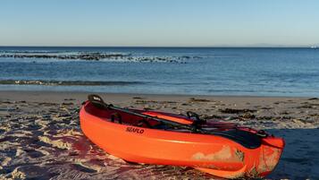 A red kayak with 'SEAFLO' branding on a sandy beach with the ocean in the background.