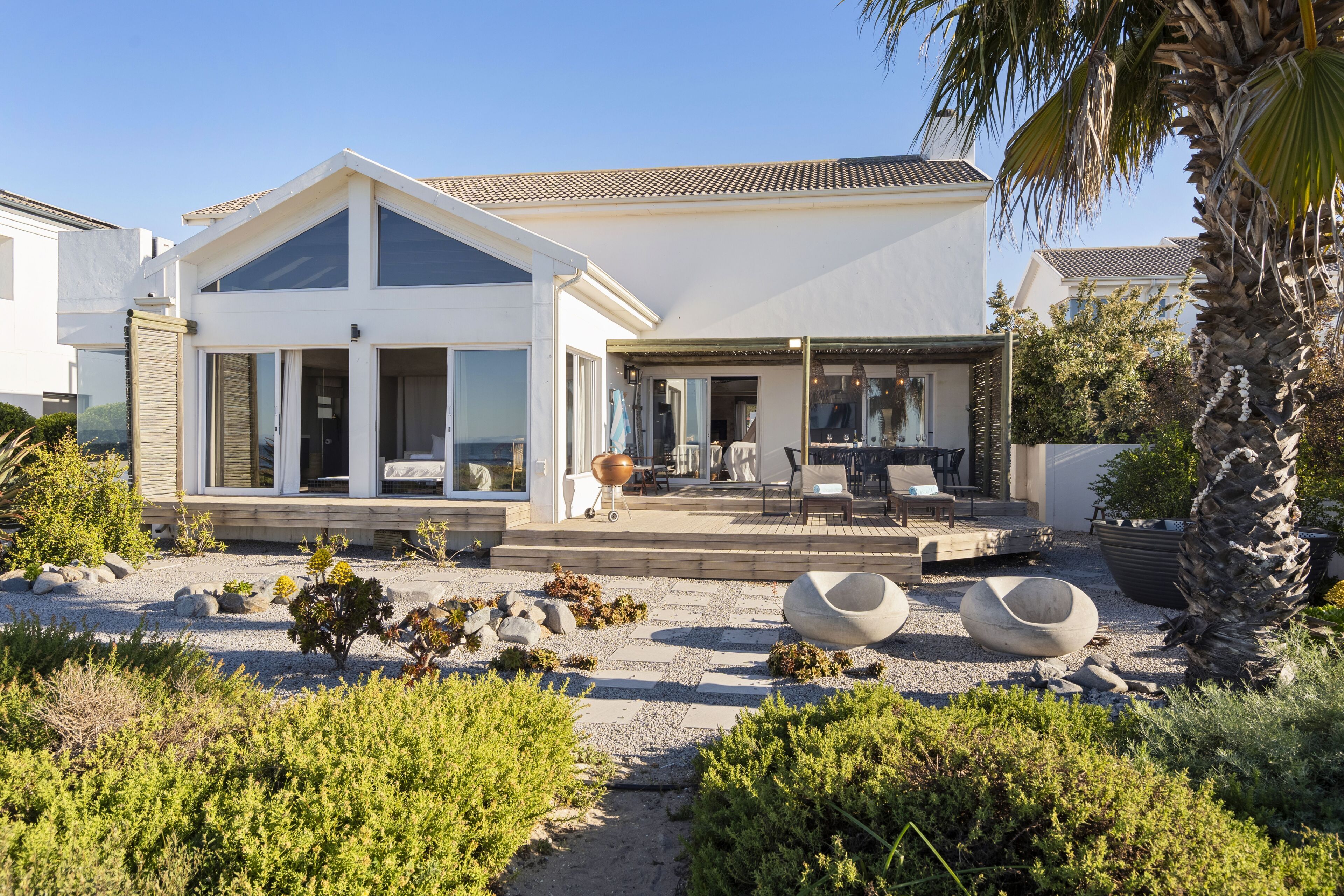 Una casa moderna con un amplio patio, mobiliario exterior y un jardín bien cuidado.