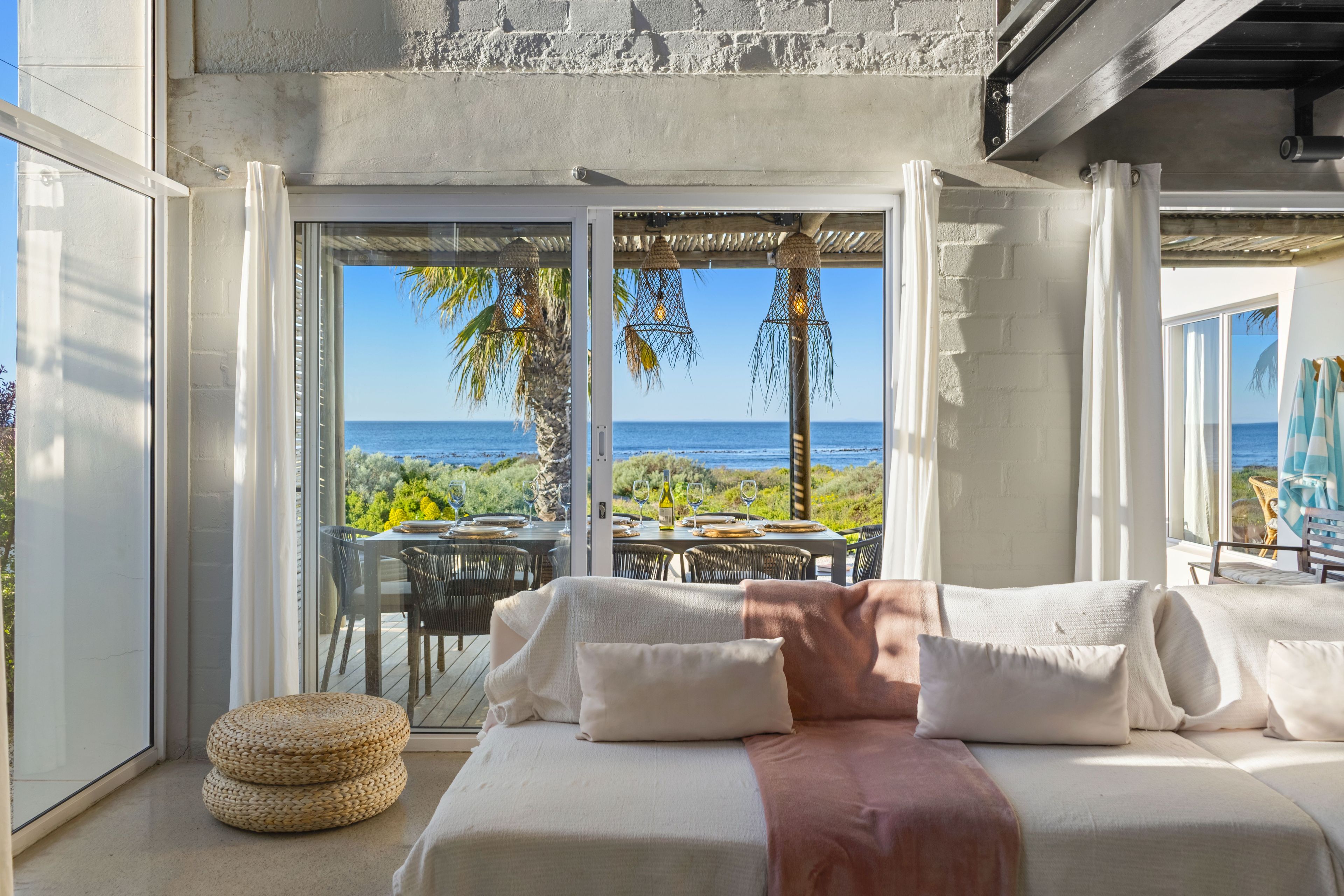 A bedroom with a bed, pillows, and a view of the ocean.