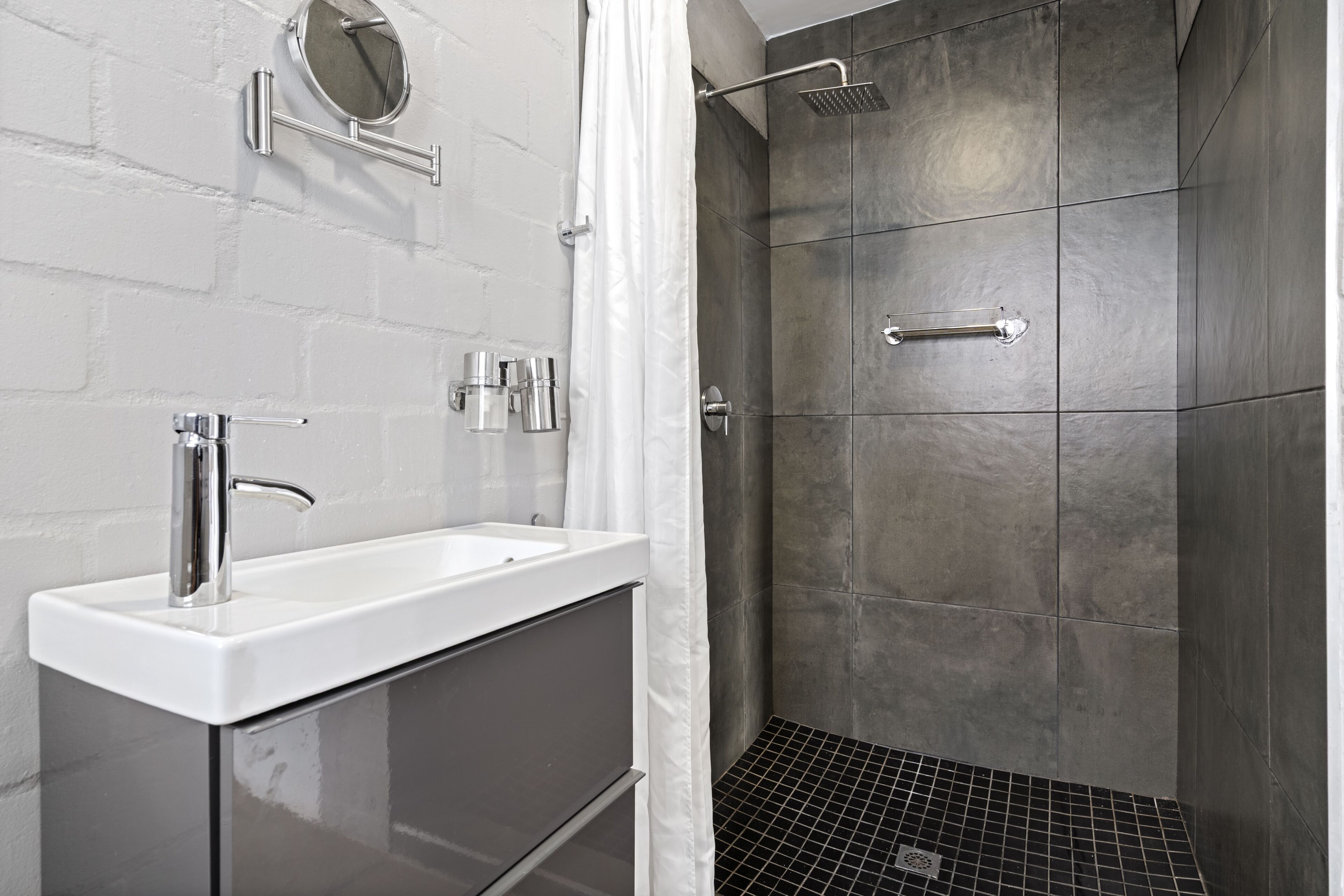 A bathroom with a white sink, a mirror, and a shower with a glass door.