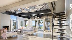 A spacious living area with a modern design, featuring a fireplace, comfortable seating, and a view of the ocean.