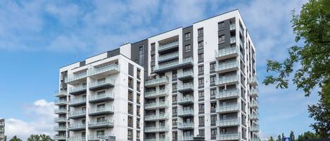 Un edificio residencial de varios pisos con balcones, un cartel de estacionamiento y una señal de paso de peatones.