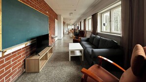 A classroom with a television, a blackboard, a sofa, and a window.