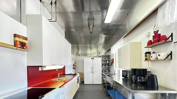 Cocina comercial con electrodomésticos de acero inoxidable, un refrigerador y una estación de café.