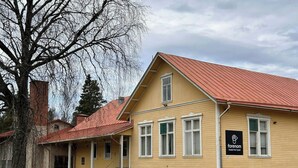 Un edificio amarillo con techo rojo, un letrero que dice 'Forenom Hostel Pori Ytre' y una chimenea de ladrillo.
