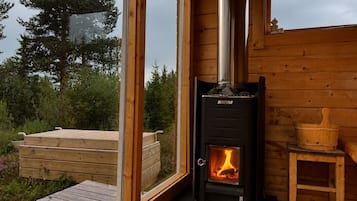 En brændeovn i en hytte med udsigt til naturen.