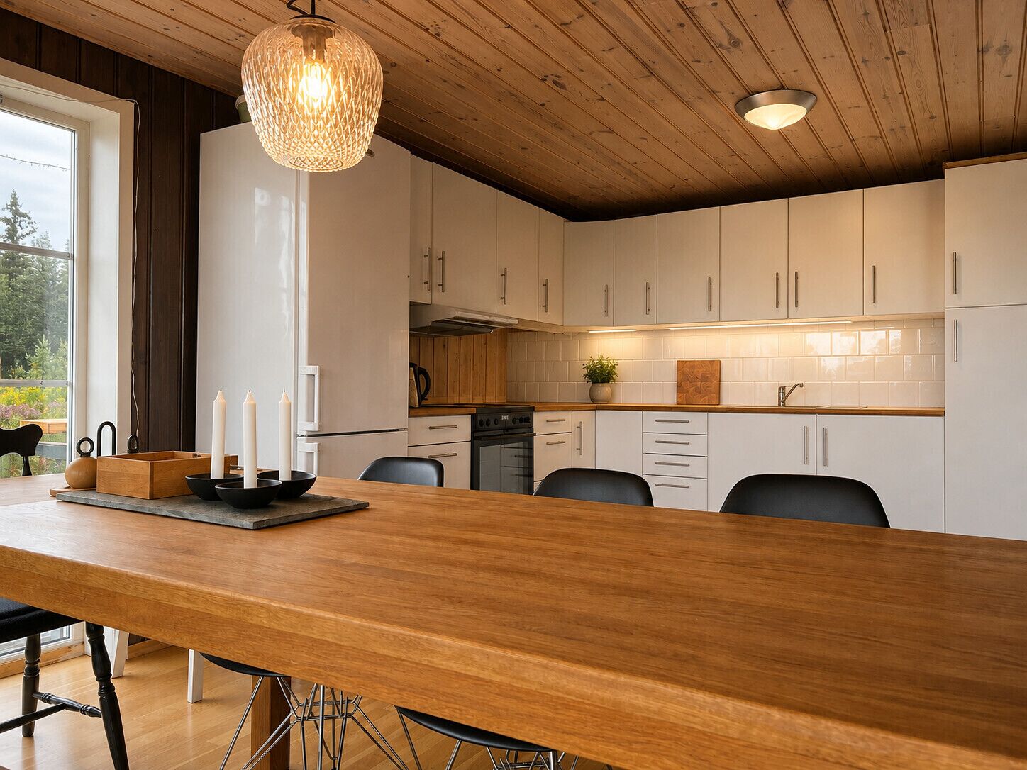 A modern kitchen with white cabinets, a wooden island, and a hanging light fixture.