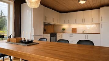 A modern kitchen with white cabinets, a wooden island, and a hanging light fixture.