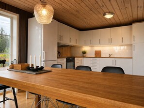 A modern kitchen with white cabinets, a wooden island, and a hanging light fixture. - Hyttetu family house with sauna in Golsfjellet (Gol)