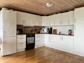 Una cocina moderna con armarios blancos, piso de madera y horno empotrado.