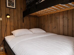A single bed with white bedding in a room with wooden walls and a sloped ceiling. - Hyttetu family house with sauna in Golsfjellet (Gol)