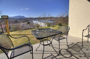 Eine Terrasse im Freien mit Tisch und Stühlen, mit Blick auf eine malerische Aussicht auf ein Gebäude und Berge.