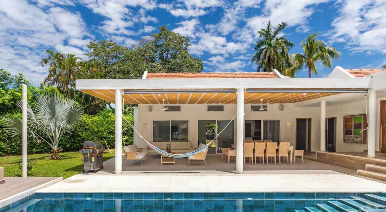 A modern house with a pool, outdoor seating, and a covered patio area.