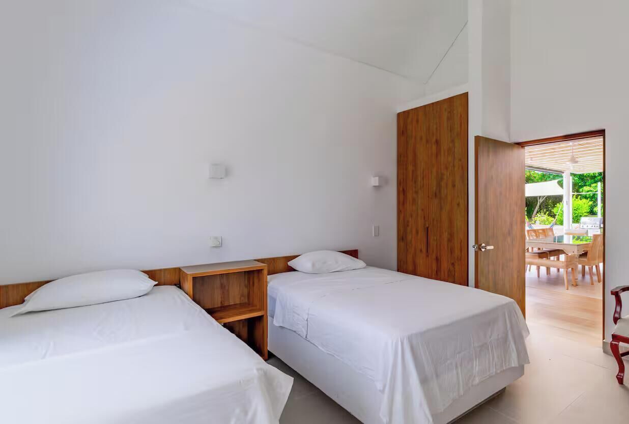 Een hotelkamer met twee enkele bedden, houten hoofdeinden, een kledingkast en uitzicht op een terras.