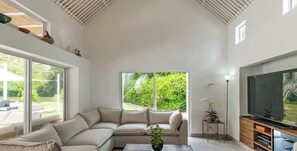 A living room with a sectional sofa, a flat-screen TV, and large windows offering a view of greenery. - TopSpot para 14 Recién Remodelado en Peñalisa! (Ricaurte)