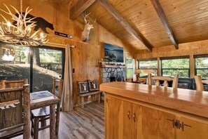 Ein rustikales Interieur mit Holzbalken, einem Steinofen und Blick ins Freie.