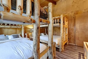 Eine rustikale Holzhütte mit Etagenbetten, einer Karomauer und Holzboden.