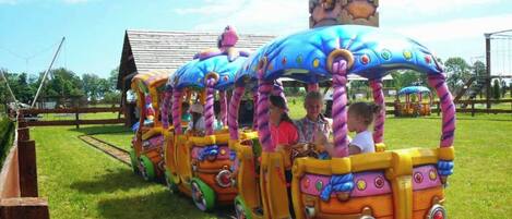 A colorful train ride with children seated inside.