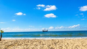 A beach with a boat in the distance, clear skies, and calm sea. - Holiday Homes Near the sea (Kamien Pomorski)