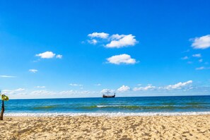 Ein Strand mit einem Boot in der Ferne, wolkenlosem Himmel und ruhiger See.