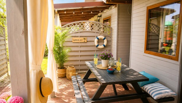 A patio with a wooden table, benches, and a sign that reads 'WAKACJE!'. - Holiday Homes Near the sea (Kamien Pomorski)
