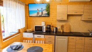 A compact kitchen with wooden cabinets, a microwave, a coffee maker, and a sink. - Holiday Homes Near the sea (Kamien Pomorski)