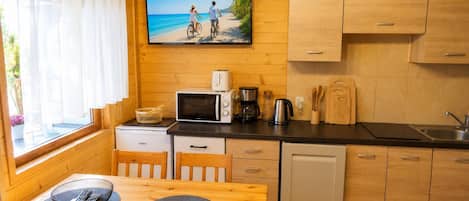 Cocina compacta con armarios de madera, microondas, cafetera y lavabo.