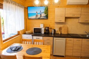Eine kompakte Küche mit Holzschränken, einer Mikrowelle, einer Kaffeemaschine und einem Spülbecken.