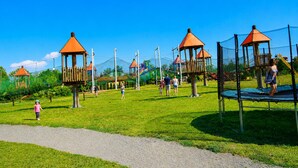 A playground with multiple play structures, including swings and climbing areas, surrounded by a grassy field. - Holiday Homes Near the sea (Kamien Pomorski)