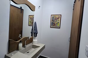 Ein Badezimmer mit Waschbecken, Spiegel und zwei gerahmten Kunstwerken an der Wand.