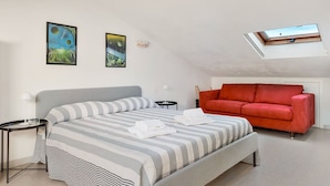 A bedroom with a bed, a red sofa, a skylight, and two wall art pieces. - [RoadToTheSea]Lerici/Private parking /terrace (Lerici)