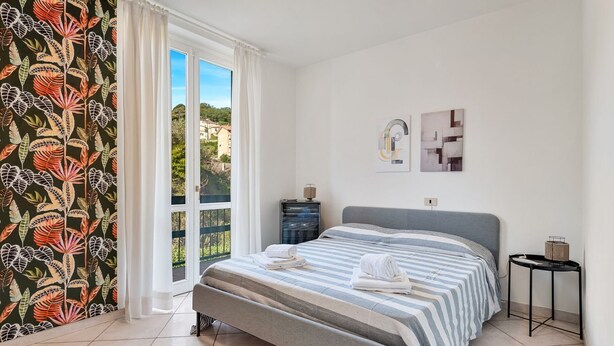 A bedroom with a bed, a nightstand, a lamp, and a view of the outside. - [RoadToTheSea]Lerici/Private parking /terrace (Lerici)