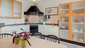 A modern kitchen with white cabinets, a black range hood, and a dining area with a table and chairs. - [RoadToTheSea]Lerici/Private parking /terrace (Lerici)