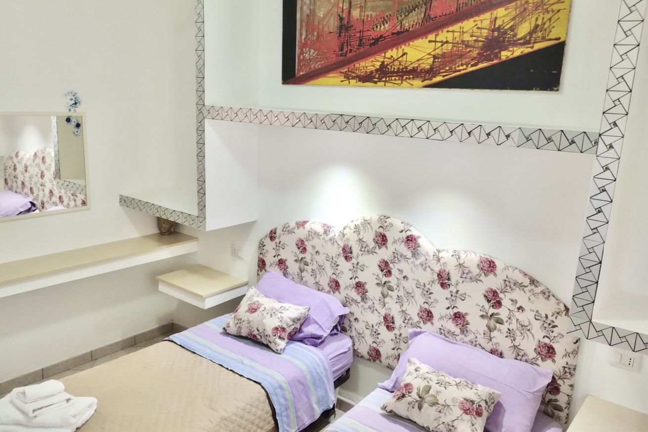Een slaapkamer met een bed, een spiegel, een plank en een schilderij aan de muur.