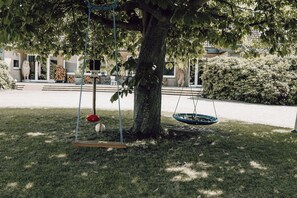 A tree with a swing set and a hanging tire swing.